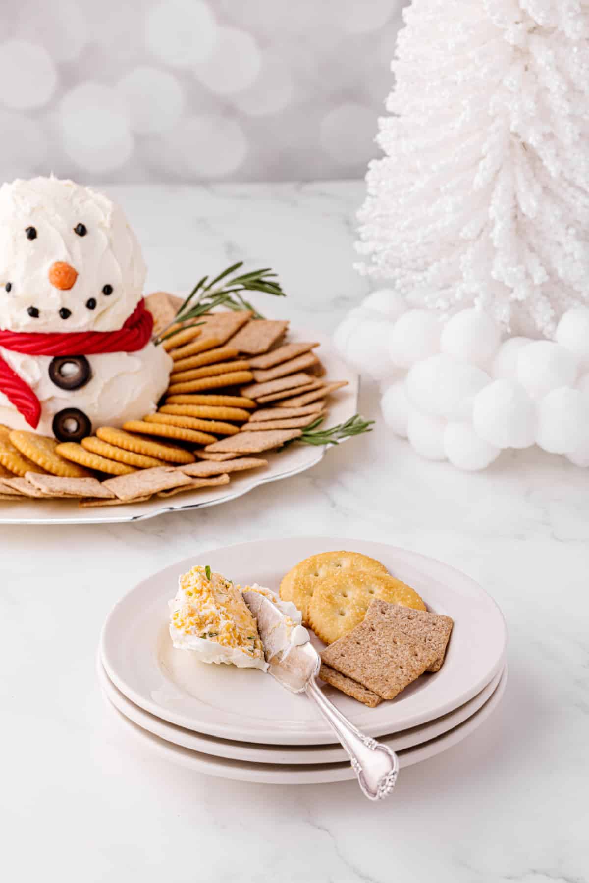 snowman cheese ball appetizer on a plate with crackers