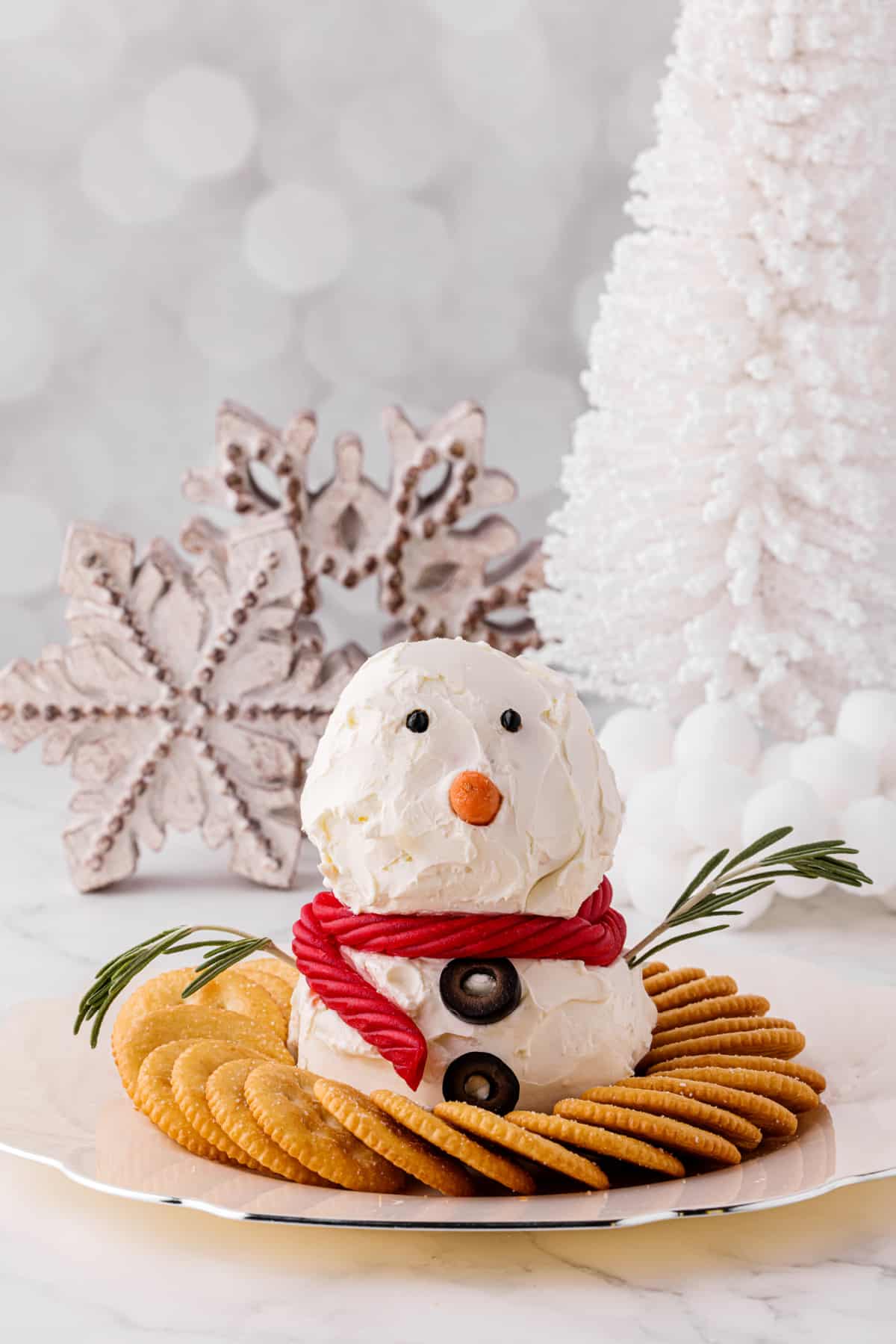 adorable snowman appetizer on a cracker tray by a white Christmas tree and ornaments