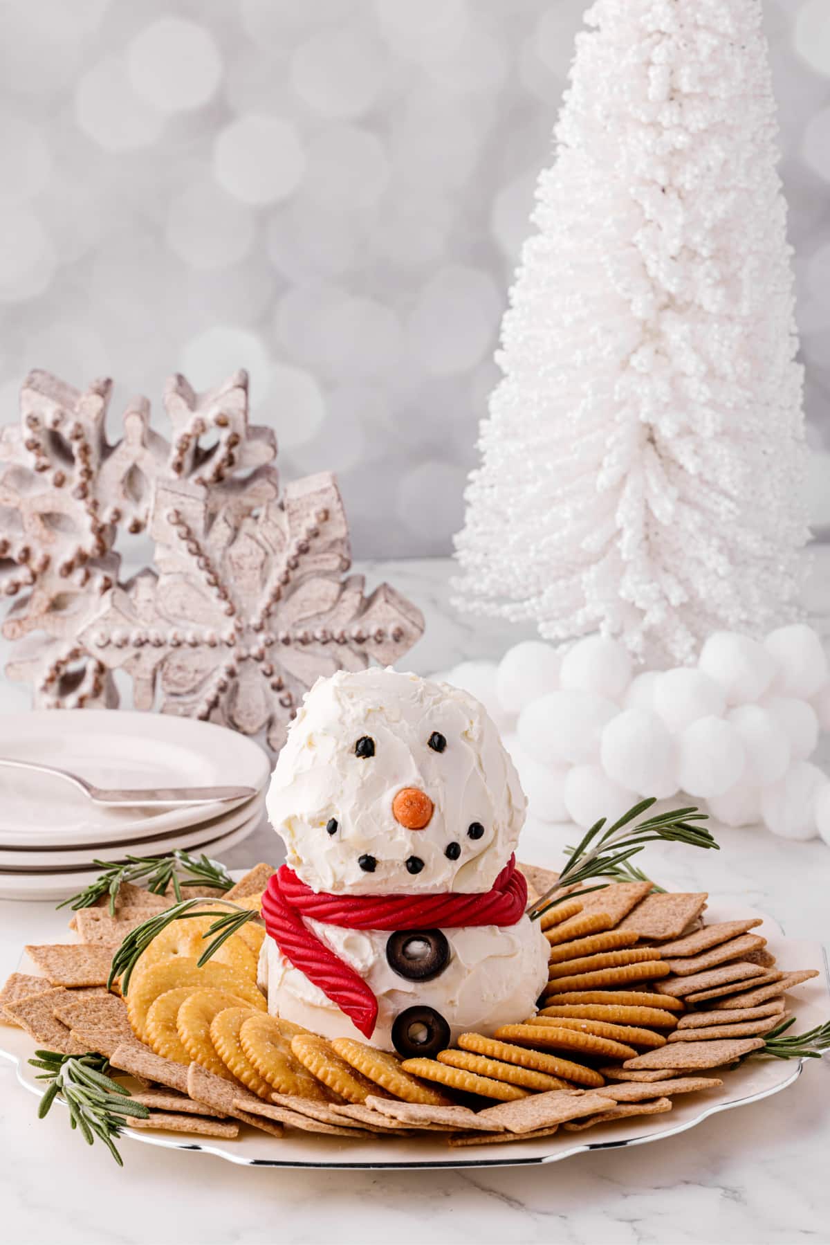 snowman appetizer on a plate with crackers with Christmas decorations