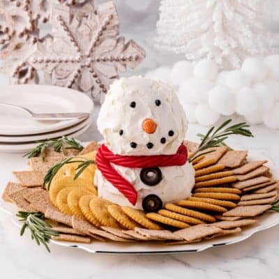 cute snowman cheeseball on a plate with crackers