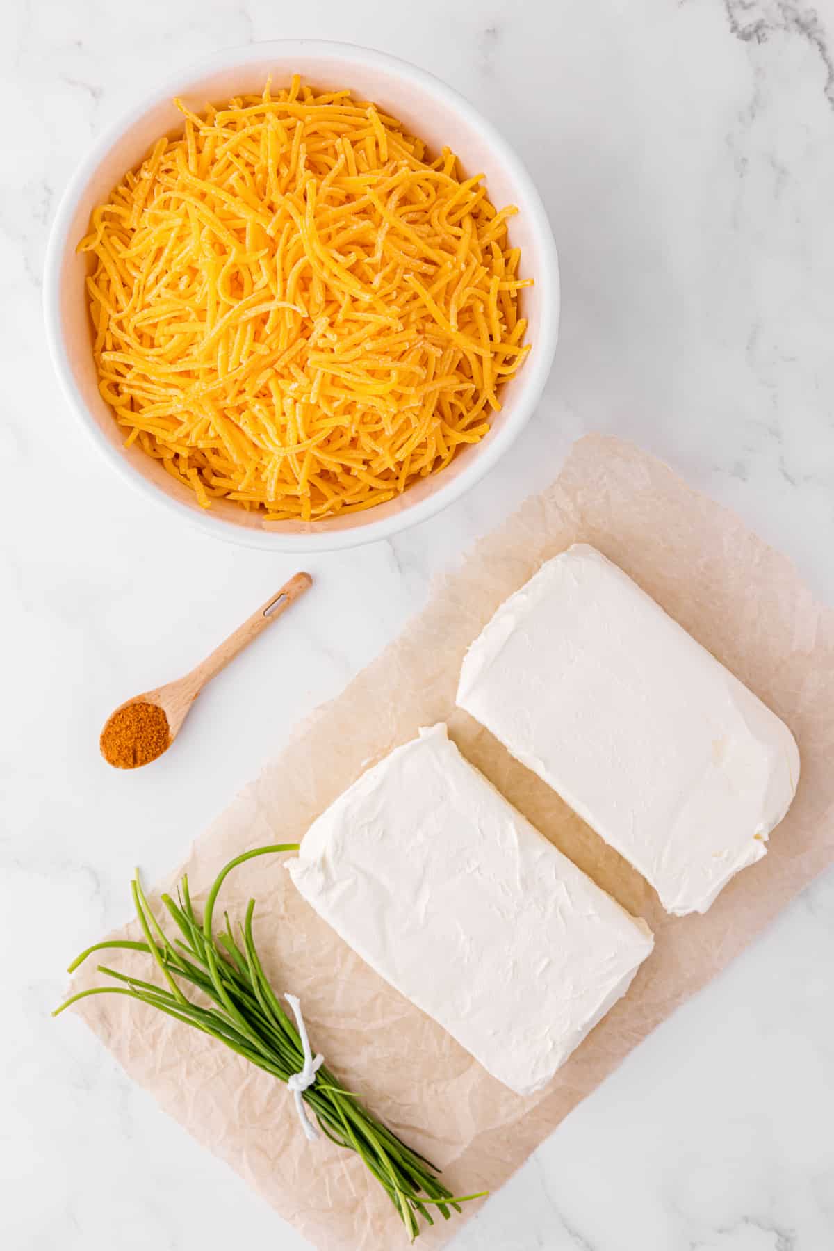 shredded cheese, rosemary sprigs and cream cheese on a cutting board