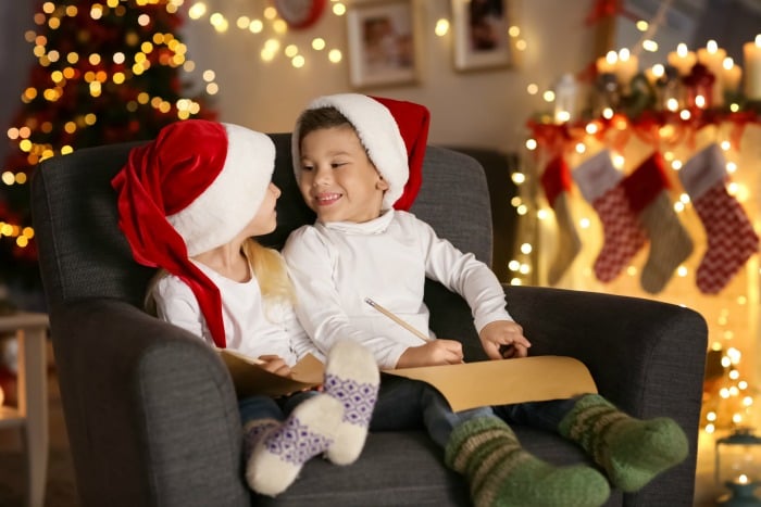 Cute kids with letters to Santa in room decorated for Christmas