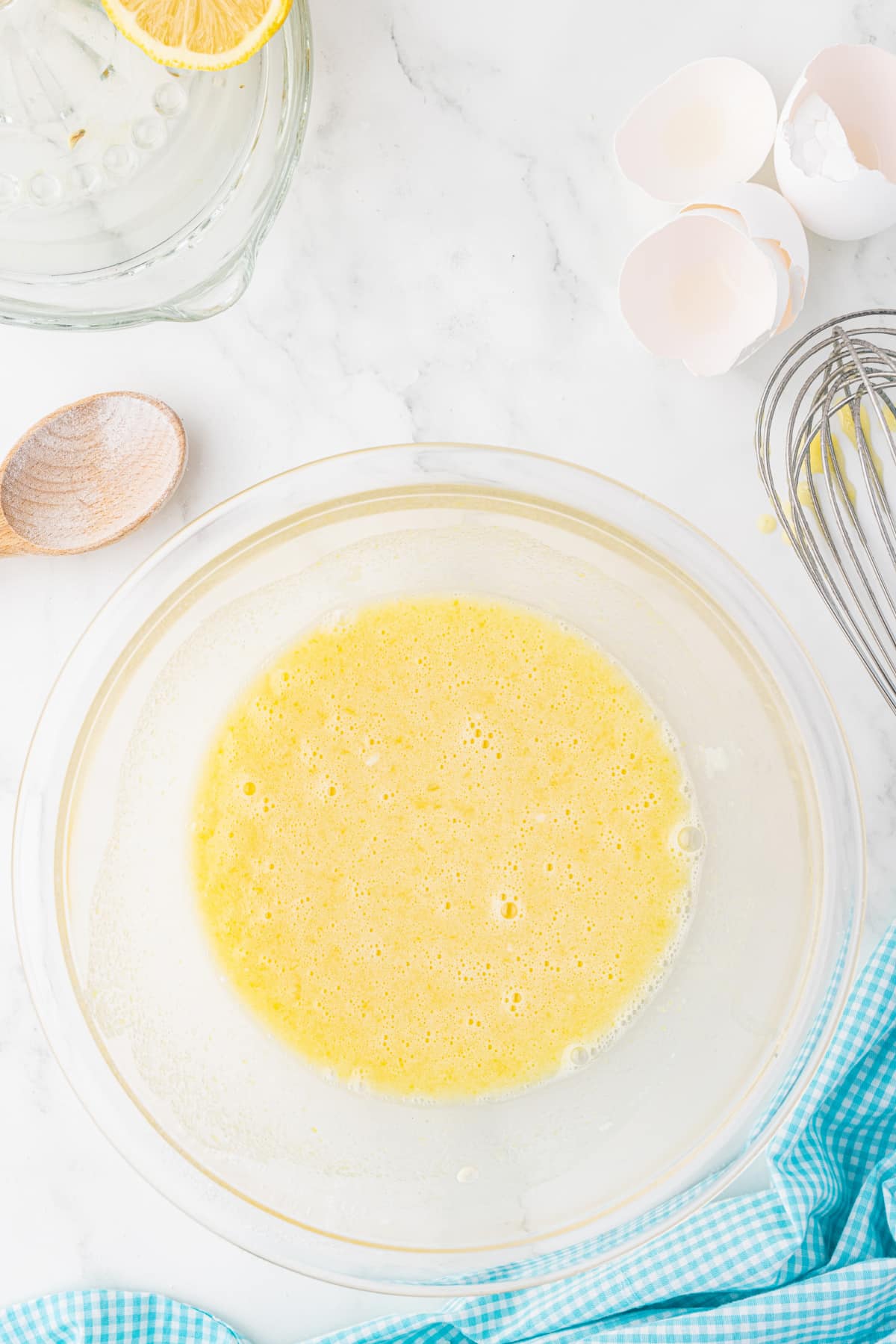 bowl of mixed lemon curd in a clear bowl on a white marble countertop