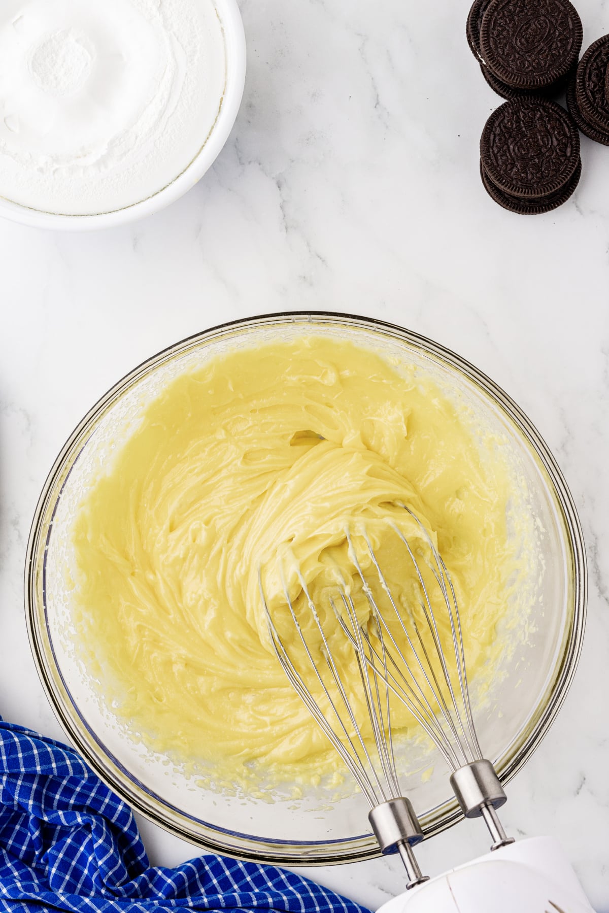 stirring yellow pudding in a bowl on a white counter