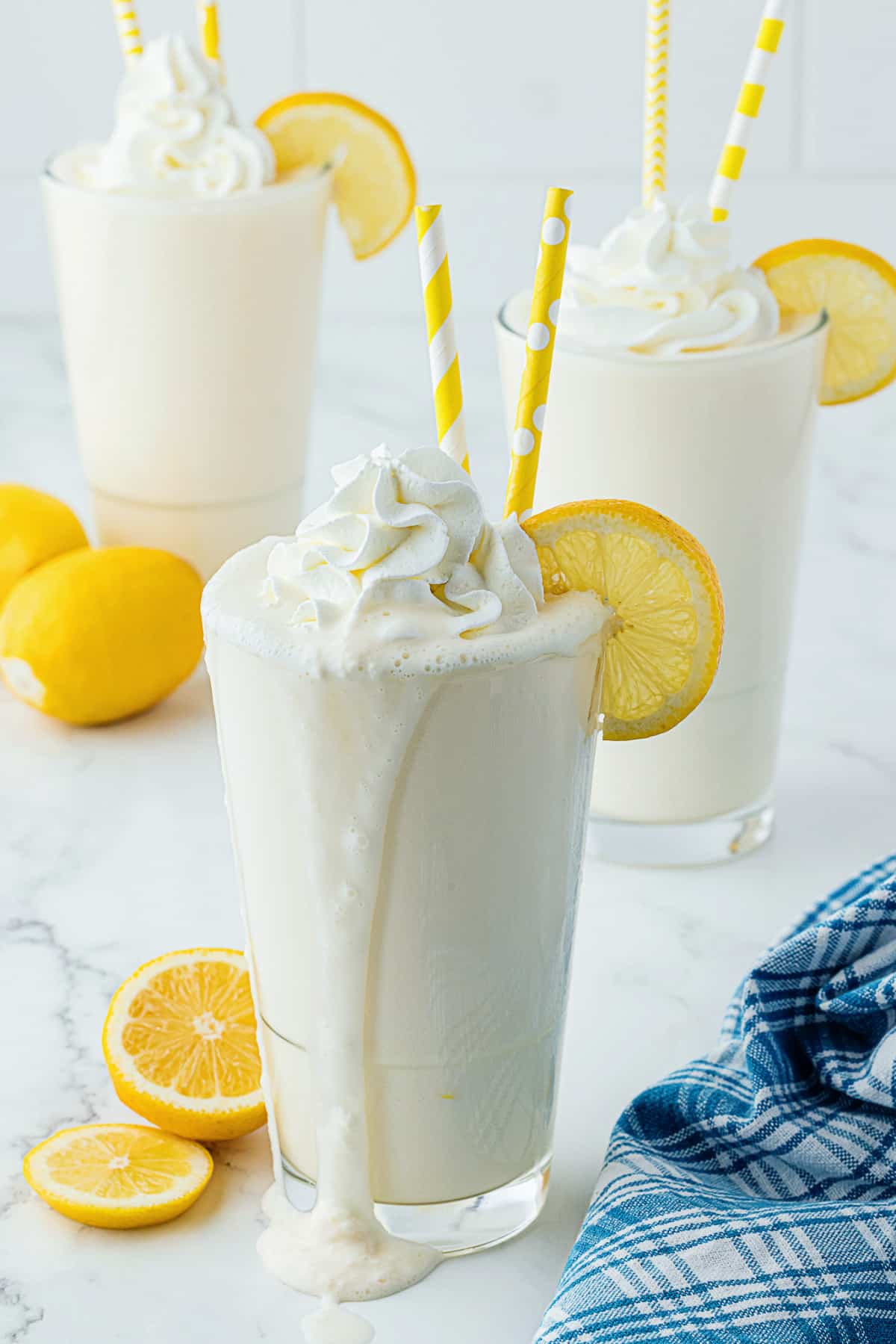 milkshake oozing over the edge onto a countertop with lemon wedge in the background