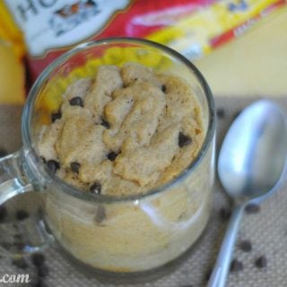 cookie in a clear class mug with a spoon and chocolate chips