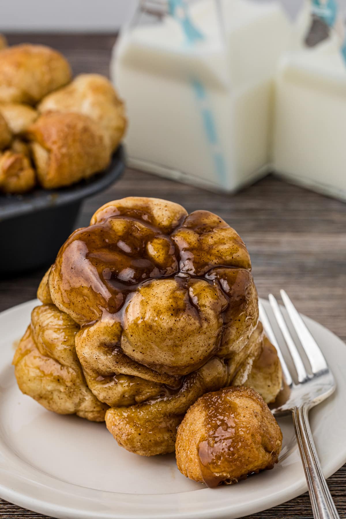 closeup of cinnamon bread monkeybread mini on a white plate with a fork