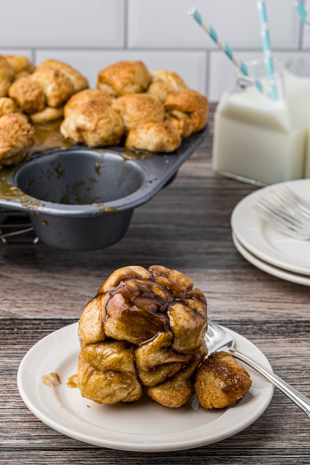 cinnamon roll monkey bread on a white plate with milk and muffin tin in background