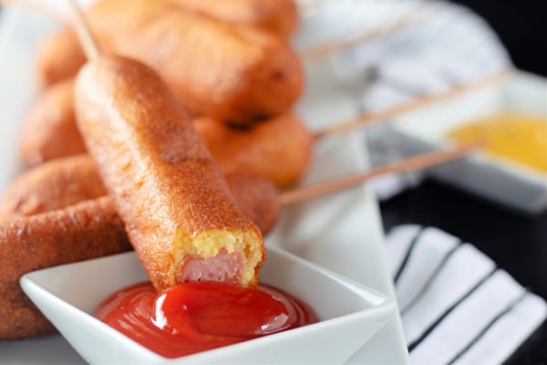 Corndog with a bite out of it dipping in ketchup