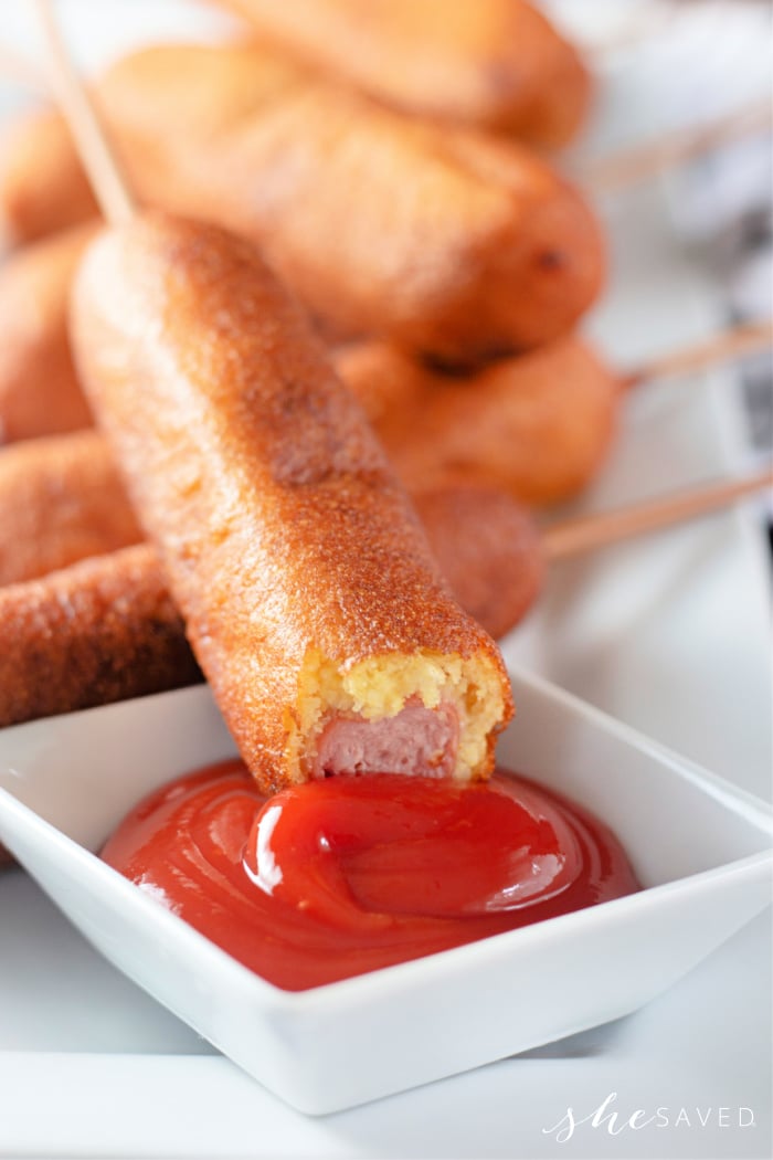 corn dog on stick dipping in ketchup