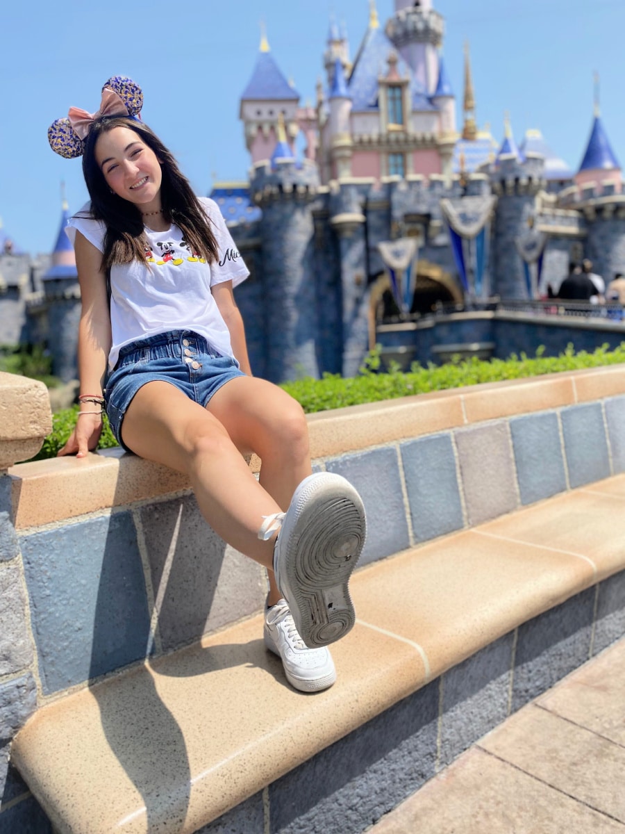 Girl in mouse ears by Disneyland Castle