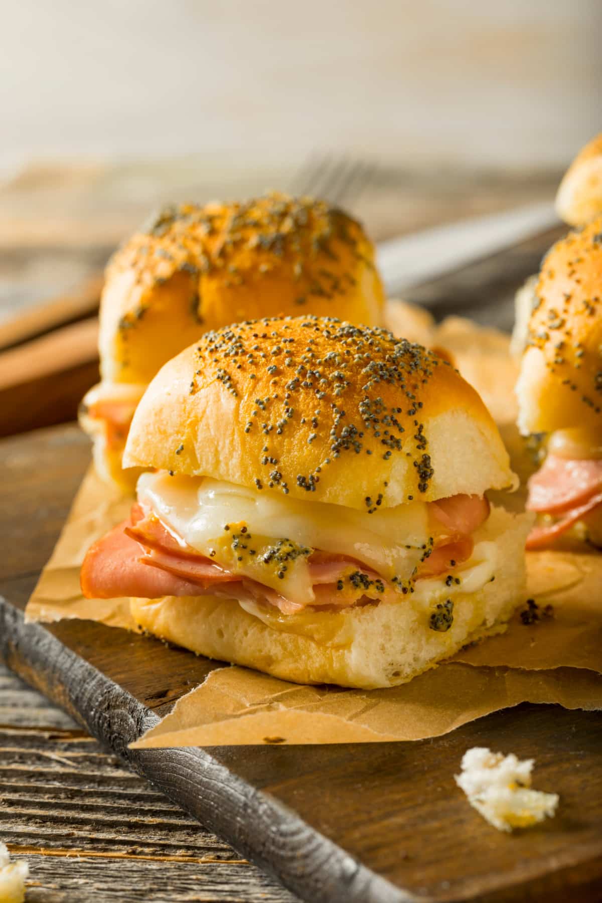 dinner roll with melted cheese and ham and poppy seeds on top