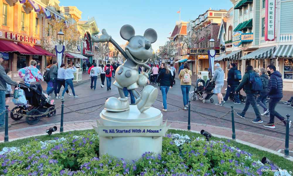 looking down mainstreet disneyland with a statue of Mickey Mouse in the center of the action