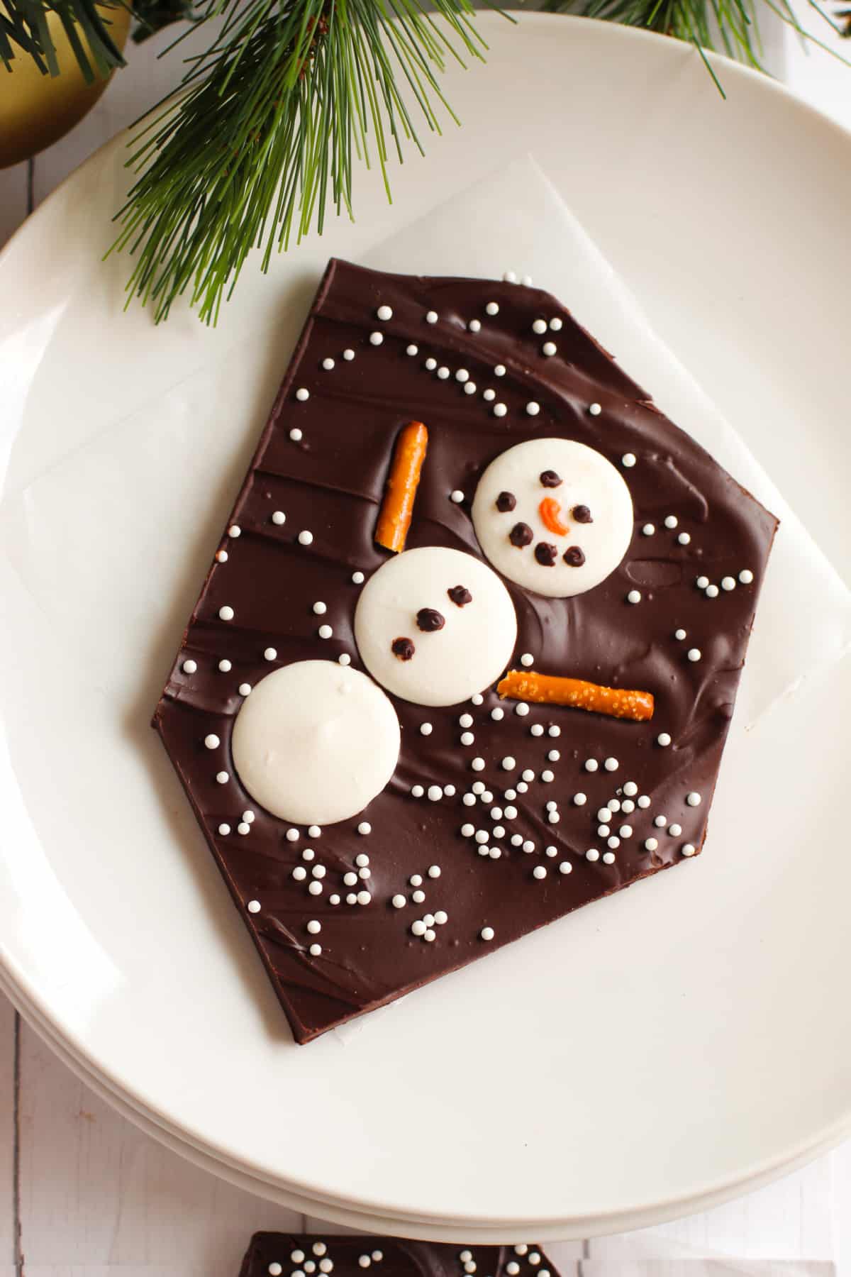 piece of snowman candy on a white plate with greenery
