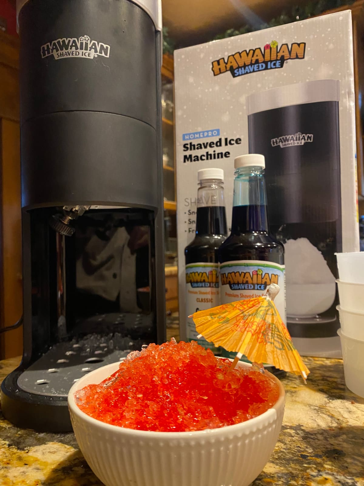 Hawaiian Shaved Ice S777 Home Pro machine with a bowl of red shaved ice and tiny umbrella