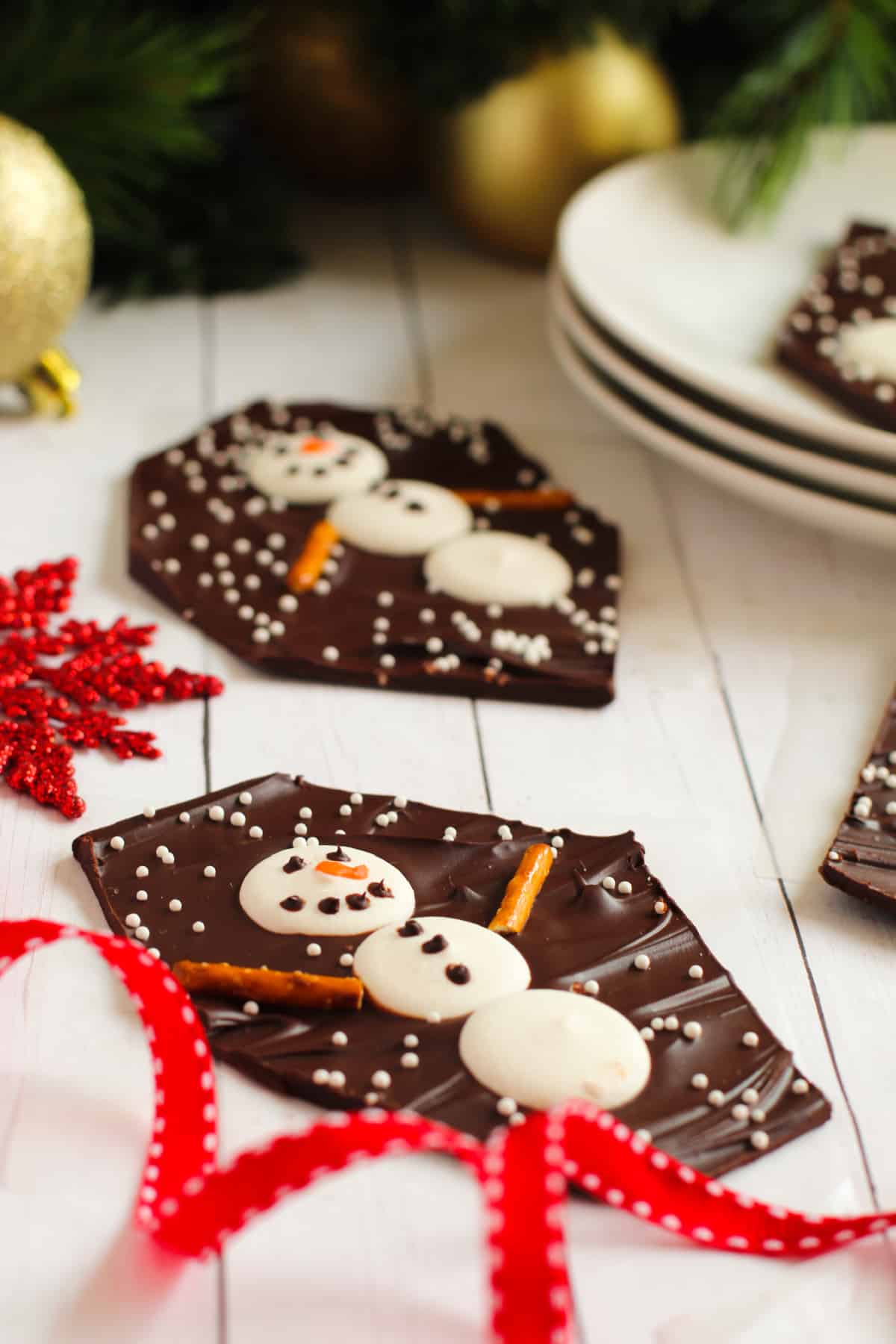 chocolate snowman candy laying on white wood with red ribbon