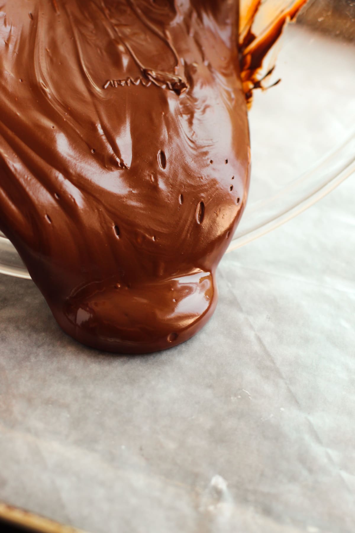 melted chocolate pouring onto a parchment paper lined cookie sheet