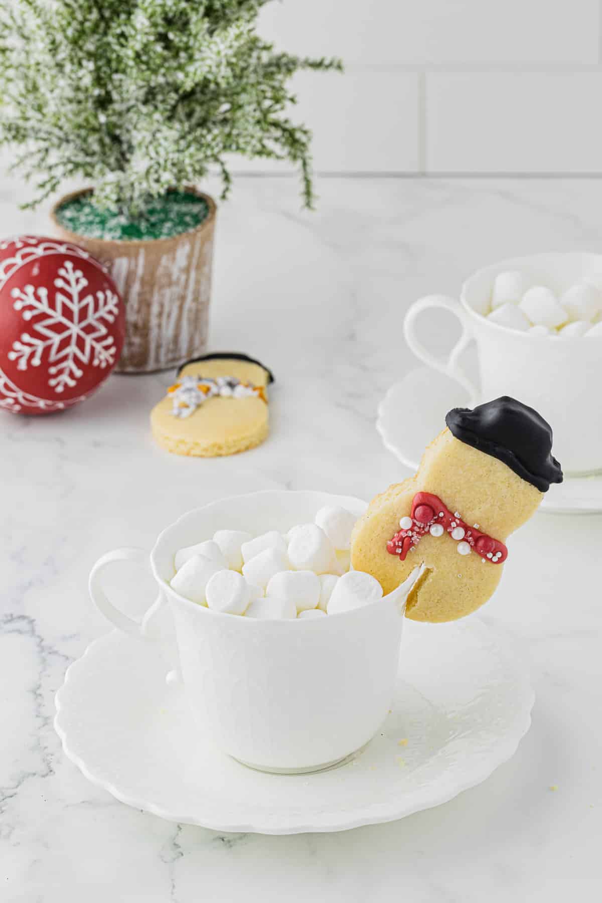 cute snowman sugar cookie mug hugger on white mug full of hot cocoa and marshmallows
