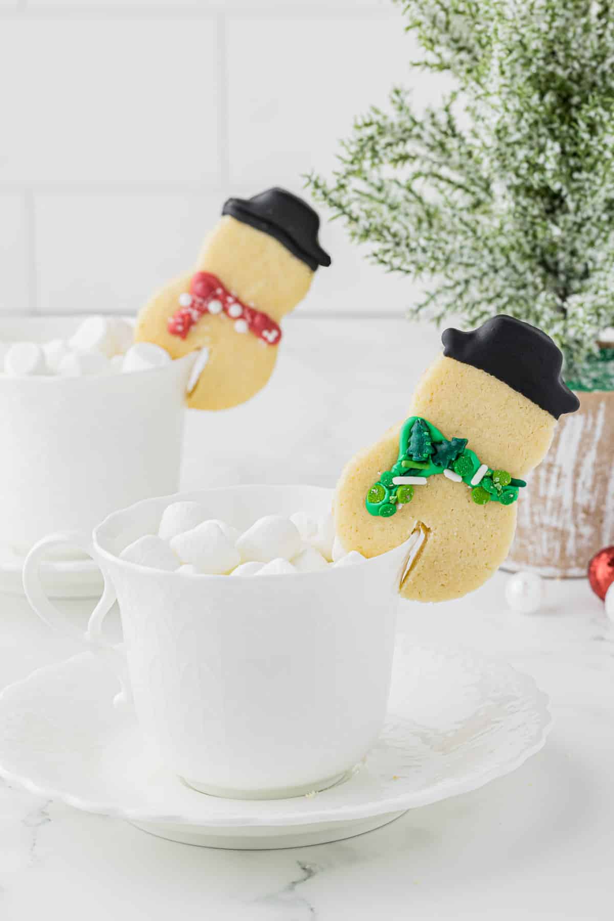 cute snowman mug huggers sitting on white mugs full of hot chocolate and marshmallows