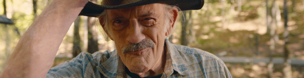 close up of a grouch looking cowboy played by Christopher Lloyd in Camp Hideout movie