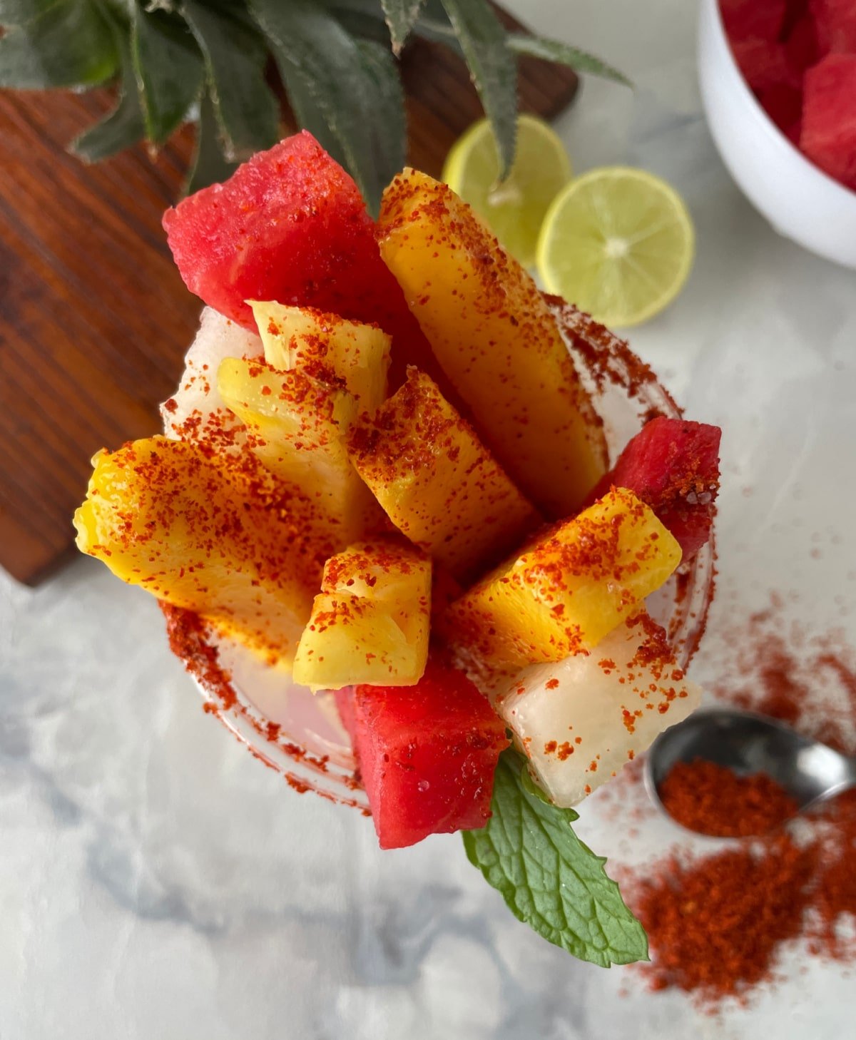 A mexican fruit cup filled with watermelon, jicama and mango spears topped with chili seasoning