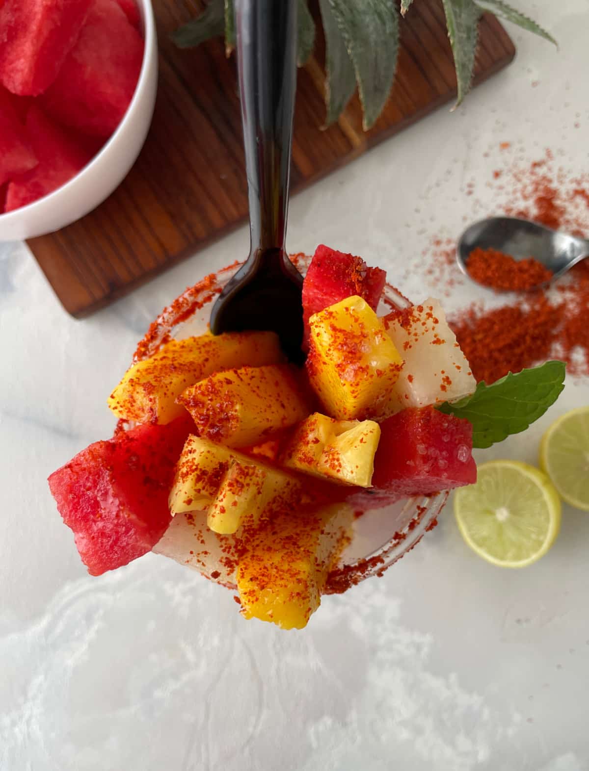A plastic fork in a mexican fruit cup topped with Tajin spice seasoning