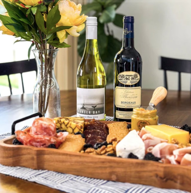Plate of meat and cheese on a table with two wine bottles