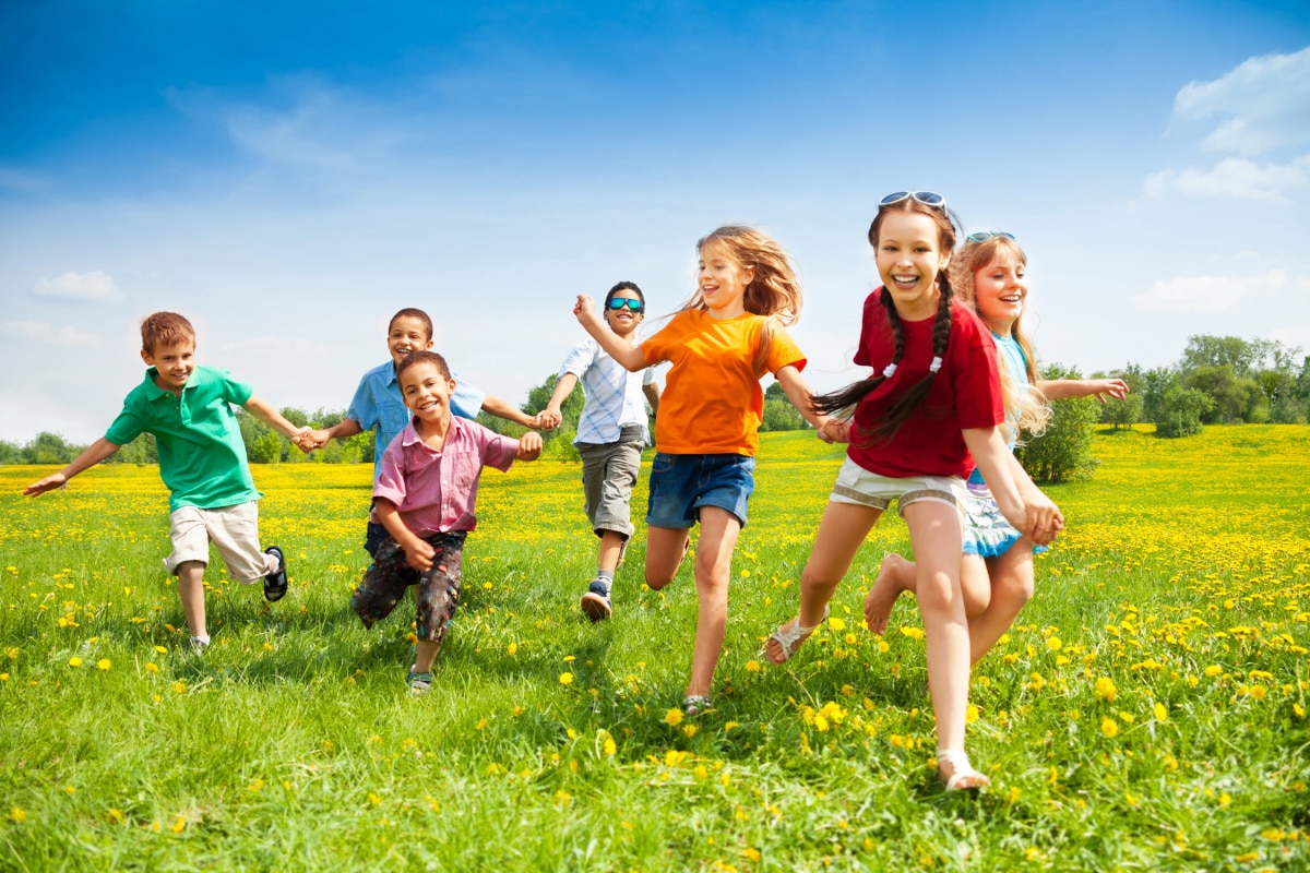 Kids running and playing on the grass in the summer time