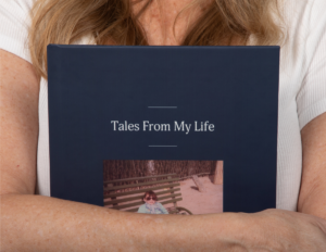 A woman hugging a Remento book that says tales from my life